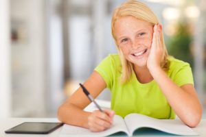 Happy teen schoolgirl being tutored at home