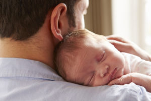 Father At Home With Sleeping Newborn Baby Daughter