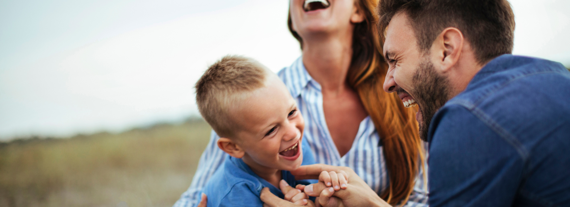 mom and dad playing with son in a park