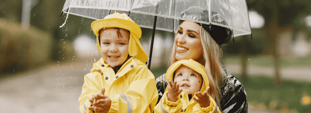nanny and kids in yellow rain suits playing in the rain