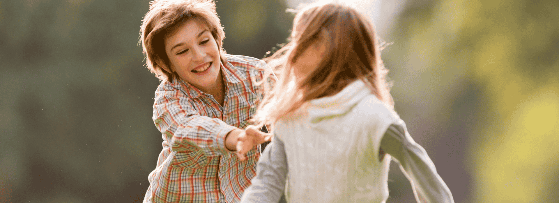 Brother and sister chasing each other in a park