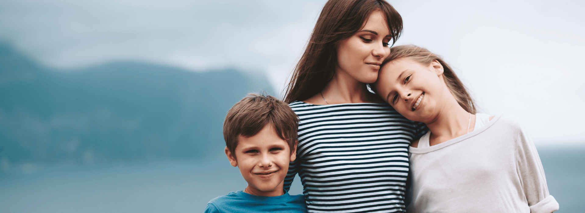 Nanny and two children outside with mountains in the background