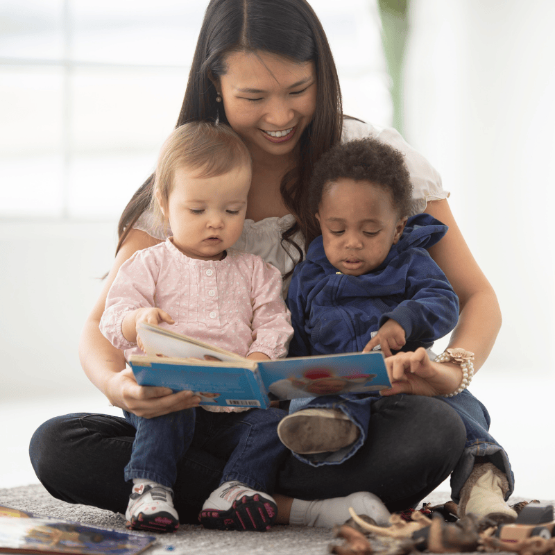 Nanny holding two children reading