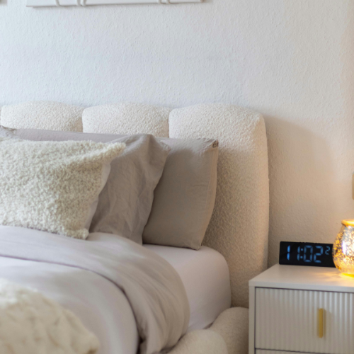 Bedroom view of a bed, bedside table and an alarm clock
