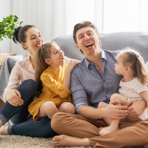 Mother, father, and their two daughters laughing while posing for a photo