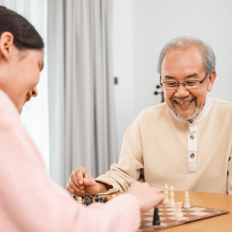 Elderly companion playing chess with old Asian man