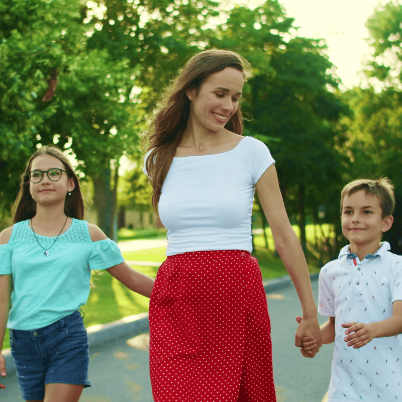 Nanny and two kids walking through the park