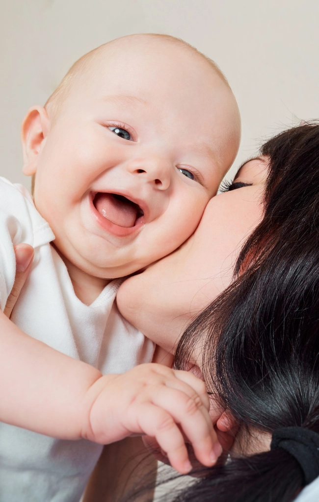 Mother kissing her happy baby on the cheek